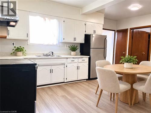 Kitchen featuring white cabinetry, stainless steel refrigerator, dual-basin sink, and wood-finish flooring - 1279 Hamilton Street, Cambridge, ON 