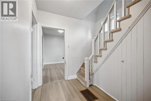 Staircase featuring white vertical wall paneling, carpeted treads, and a classic wood newel post with built-in storage cabinet and wood-finish flooring - 1279 Hamilton Street, Cambridge, ON 