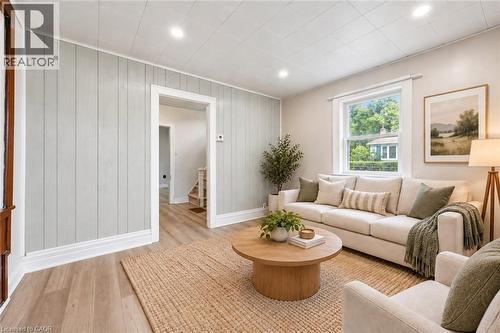 Living area featuring vertical plank accent wall, wood-finish flooring, and recessed lighting - 1279 Hamilton Street, Cambridge, ON 