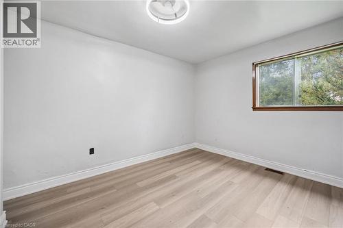 Wood-finish flooring, neutral wall tones, sliding window with wood-trim framing, and a flush-mount ceiling light fixture - 1279 Hamilton Street, Cambridge, ON 