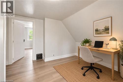 Room featuring light-toned wood-finish flooring, neutral wall paint, a slanted ceiling, and a paneled interior door - 1279 Hamilton Street, Cambridge, ON 