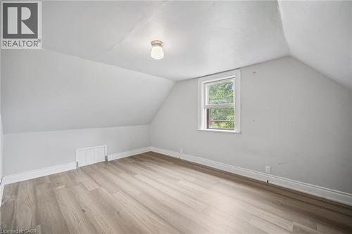 Room featuring slanted ceilings, neutral wall tones, wood-finish flooring, a single window, and a central flush-mount ceiling light - 1279 Hamilton Street, Cambridge, ON 