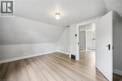 Neutral-toned wood-finish flooring, white walls with slanted ceilings, and a classic-style interior door with hardware - 1279 Hamilton Street, Cambridge, ON 