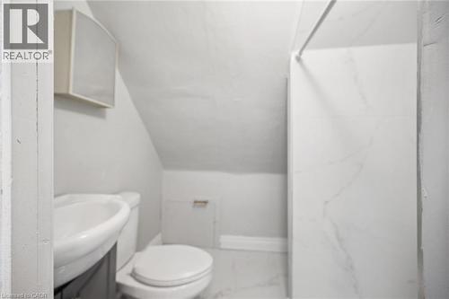Wall-mounted medicine cabinet, white pedestal sink, dual-flush toilet, and shower surround featuring large-format stone-patterned tiling - 1279 Hamilton Street, Cambridge, ON 
