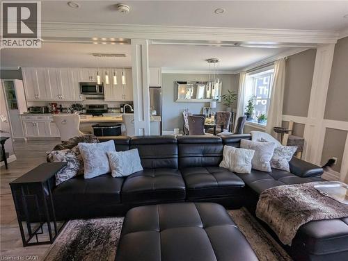 Open-concept interior featuring white shaker-style cabinetry, recessed ceiling lighting, crown molding, vertical column detailing, and wood-finish flooring - 326 Ottawa Street, Hamilton, ON 