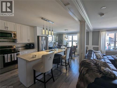 Kitchen featuring white cabinetry, stone-surface island, stainless steel appliances, wood-finish flooring, and crown molding - 326 Ottawa Street, Hamilton, ON 