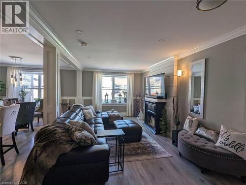 Open-concept interior featuring wood-finish flooring, recessed lighting, crown molding, paneled wall detailing, and a black fireplace mantel - 326 Ottawa Street, Hamilton, ON 