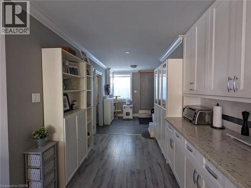 Kitchen featuring white shaker-style cabinetry, stone-finish countertops, wood-finish flooring, and crown molding - 326 Ottawa Street, Hamilton, ON 