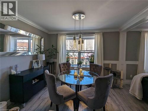 Dining space featuring wood-finish flooring, wainscoting, a multi-light cylindrical pendant fixture, and a large wall-mounted mirror - 326 Ottawa Street, Hamilton, ON 