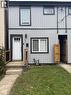 Exterior facade featuring vertical metal siding with dark-trimmed windows, a multi-pane front door, and a concrete entry stoop with wooden railings - 197 Ferguson Avenue S, Hamilton, ON 