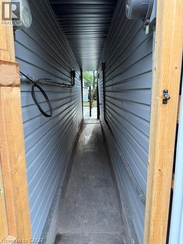 Exterior side passage featuring horizontal vinyl siding, wood-framed entry, and concrete flooring - 197 Ferguson Avenue S, Hamilton, ON 