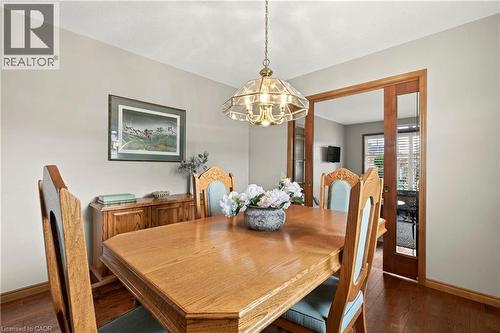 Dining area featuring wood-finish flooring, a tiered metal pendant light fixture, and a wood-framed sliding glass panel door - 53 Bastille Street, Hamilton, ON 