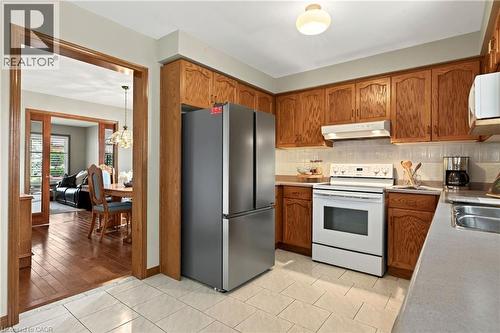 Kitchen featuring natural wood cabinetry, solid surface countertops, tiled flooring, stainless steel French-door refrigerator, and white electric range - 53 Bastille Street, Hamilton, ON 