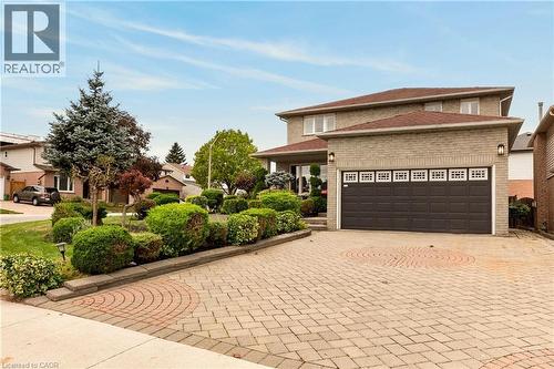 Two-story brick exterior featuring a multi-car garage, expansive patterned stone driveway, and curated landscaping - 53 Bastille Street, Hamilton, ON 