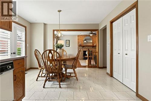 Dining area featuring large-format ceramic tile flooring, built-in dual-panel closet doors, and wood trim detailing, incorporating a glass-paned door and a hanging pendant light fixture - 53 Bastille Street, Hamilton, ON 