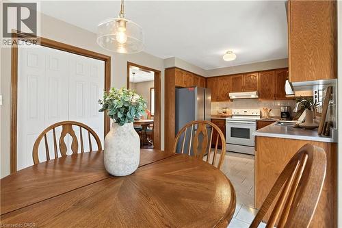 Kitchen featuring stained wood cabinetry, tile flooring, built-in range, and a glass pendant light fixture - 53 Bastille Street, Hamilton, ON 