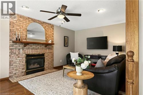 Full-height brick fireplace surround with an arched mantle, inset gas fireplace, wood-finish flooring, recessed lighting, and ceiling fan - 53 Bastille Street, Hamilton, ON 
