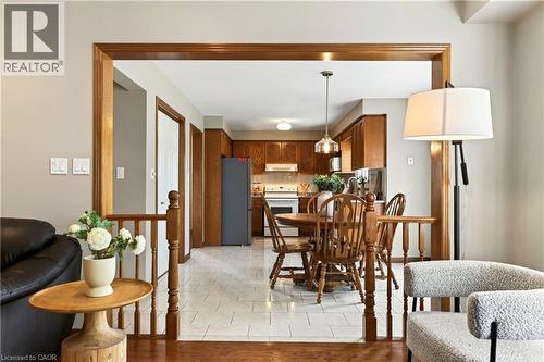 Kitchen featuring wood cabinetry, tile flooring, and a pendant light fixture, framed by a wood-trimmed portal with a spindle railing - 53 Bastille Street, Hamilton, ON 