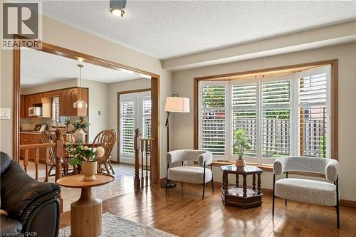 Living area featuring hardwood flooring, a bay window with plantation shutters, and a wood-cased architectural opening - 53 Bastille Street, Hamilton, ON 