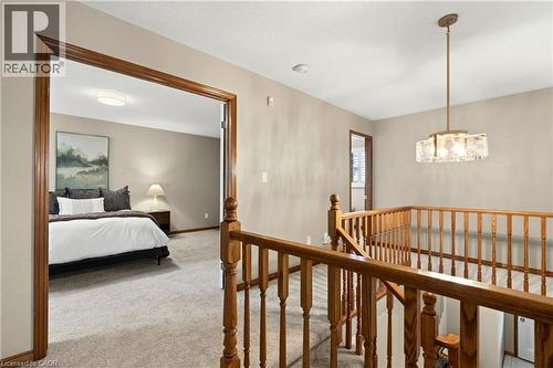 Natural wood-tone balustrade railing featuring decorative turned spindles, tiered glass-shade chandelier, and neutral wall tones - 53 Bastille Street, Hamilton, ON 