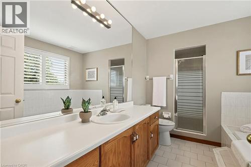 Bathroom featuring a vanity with white countertop, integrated sink, wood cabinetry, wall-to-wall mirror, and shuttered window - 53 Bastille Street, Hamilton, ON 
