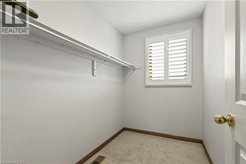 Walk-in storage space featuring neutral carpeting, a built-in wire shelving system, and a window with plantation-style shutters - 53 Bastille Street, Hamilton, ON 