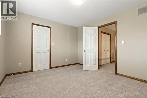 Room featuring neutral-toned carpeting, six-panel interior doors, and wood-finish door casings - 53 Bastille Street, Hamilton, ON 