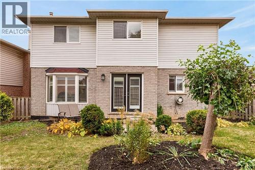 Two-story exterior featuring light-toned brick and horizontal siding, double glass-paneled rear entry doors, and a multi-pane bay window - 53 Bastille Street, Hamilton, ON 
