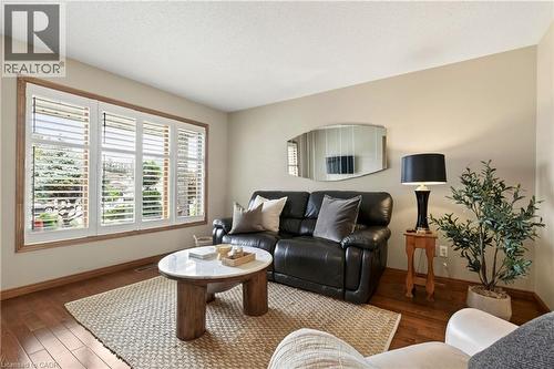 Wood-finish flooring, large window with multi-panel white plantation shutters, and neutral wall paint - 53 Bastille Street, Hamilton, ON 
