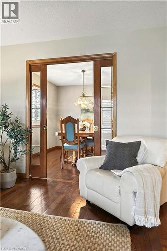 Solid wood-framed glass pocket doors, wood-finish flooring, and a multi-light metal pendant fixture - 53 Bastille Street, Hamilton, ON 