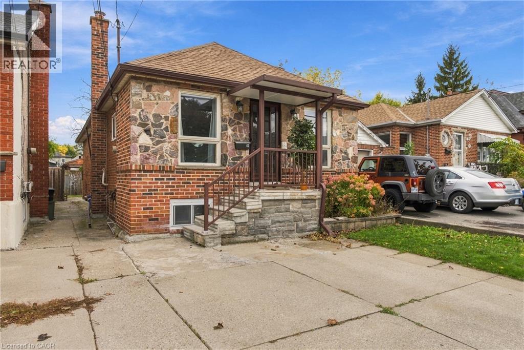 Exterior facade featuring mixed-material stone and brick masonry, covered front entryway with metal railings, and private concrete driveway - 81 East 23Rd Street, Hamilton, ON