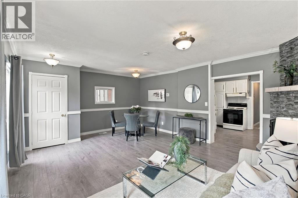 Stone-surround fireplace, wood-finish flooring, white crown molding, chair rail trim, and recessed lighting fixtures - 81 East 23Rd Street, Hamilton, ON