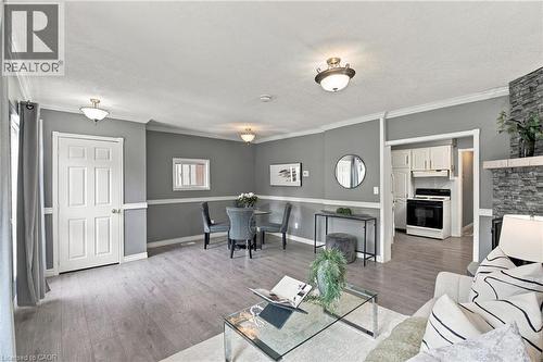 Stone-surround fireplace, wood-finish flooring, white crown molding, chair rail trim, and recessed lighting fixtures - 81 East 23Rd Street, Hamilton, ON 