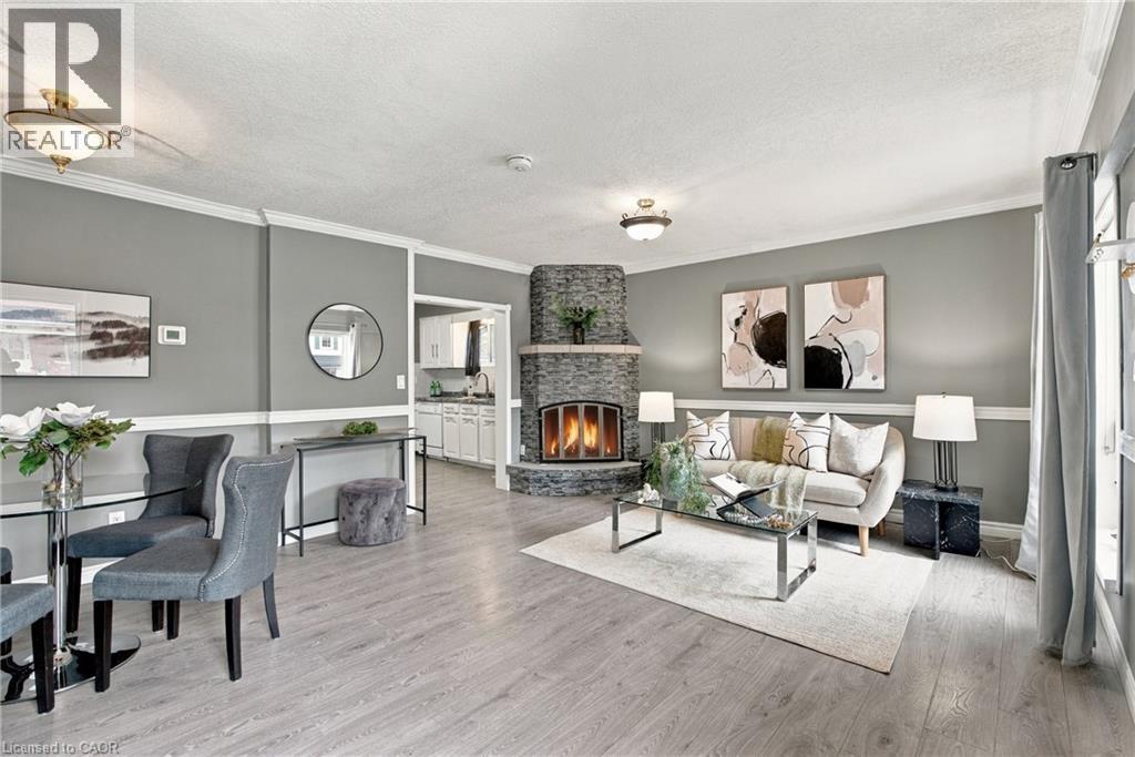 Corner stone-faced fireplace with a hearth, wood-finish flooring, two-tone walls with chair rail molding, crown molding, and recessed ceiling lighting - 81 East 23Rd Street, Hamilton, ON
