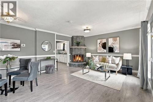 Corner stone-faced fireplace with a hearth, wood-finish flooring, two-tone walls with chair rail molding, crown molding, and recessed ceiling lighting - 81 East 23Rd Street, Hamilton, ON 