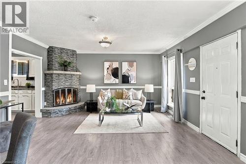Corner fireplace featuring stacked stone masonry and a raised hearth, wood-finish flooring, and crown molding - 81 East 23Rd Street, Hamilton, ON 