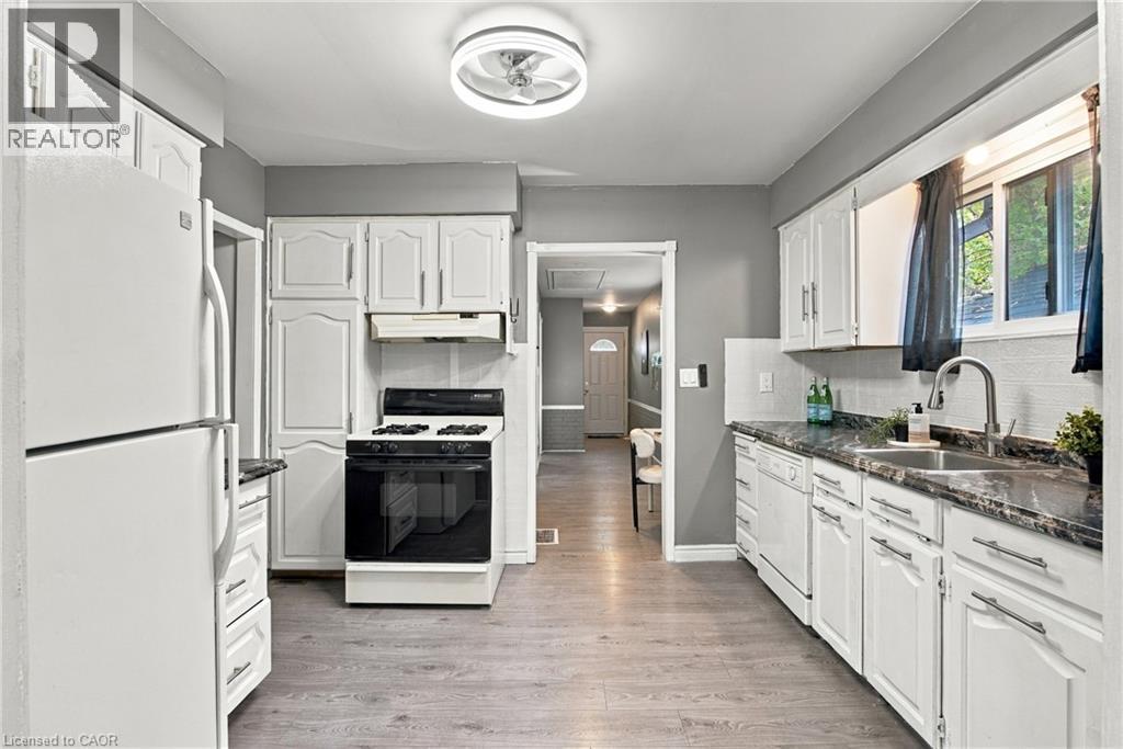 Kitchen featuring white cabinetry, wood-finish flooring, dark stone-patterned countertops, a stainless steel faucet, and a flush-mount ceiling fixture - 81 East 23Rd Street, Hamilton, ON
