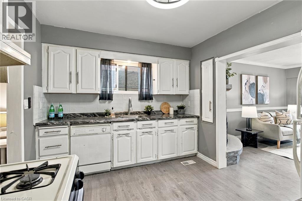 Kitchen featuring white cabinetry, dark stone-finish countertops, stainless steel undermount sink, and wood-finish flooring - 81 East 23Rd Street, Hamilton, ON