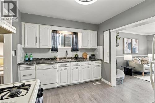 Kitchen featuring white cabinetry, dark stone-finish countertops, stainless steel undermount sink, and wood-finish flooring - 81 East 23Rd Street, Hamilton, ON 