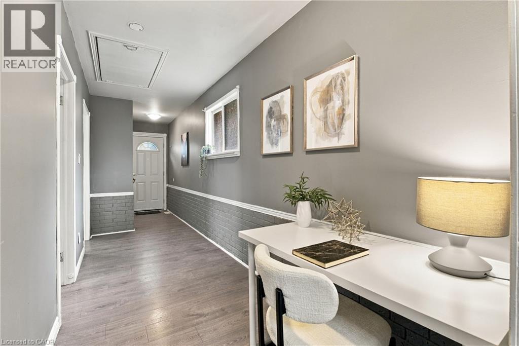 Hallway featuring wood-finish flooring, painted brick wainscoting, a flush-mount ceiling light, and a single-entry door with glass detailing - 81 East 23Rd Street, Hamilton, ON