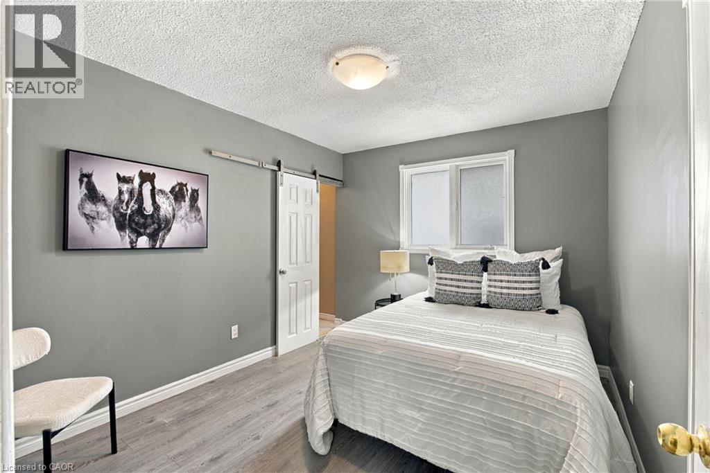 Neutral-toned interior space featuring wood-finish flooring, sliding barn door, and flush-mount ceiling lighting - 81 East 23Rd Street, Hamilton, ON
