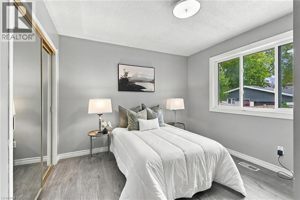 Neutral-toned interior featuring wood-finish flooring, a large horizontal window, and a sliding-door closet with a mirrored finish - 81 East 23Rd Street, Hamilton, ON