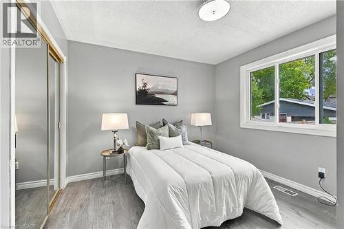 Neutral-toned interior featuring wood-finish flooring, a large horizontal window, and a sliding-door closet with a mirrored finish - 81 East 23Rd Street, Hamilton, ON 