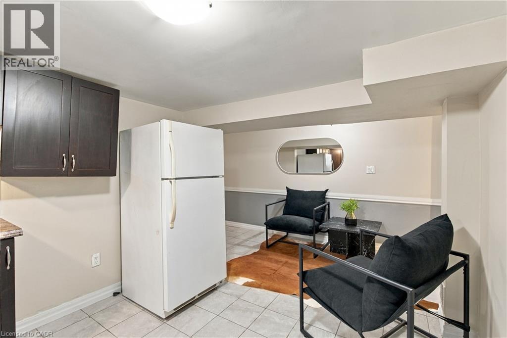 Dark-toned upper cabinetry, tile flooring, and wall-mounted oval mirror - 81 East 23Rd Street, Hamilton, ON
