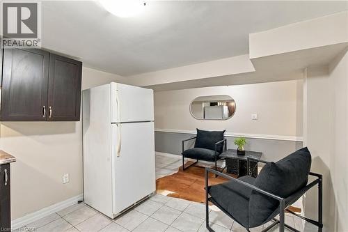 Dark-toned upper cabinetry, tile flooring, and wall-mounted oval mirror - 81 East 23Rd Street, Hamilton, ON 