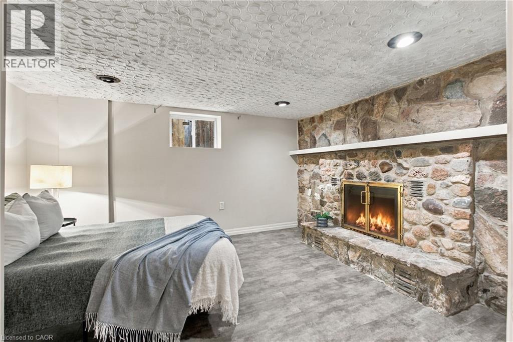 Floor-to-ceiling stone fireplace with an integrated hearth, textured ceiling finish, recessed lighting, and wood-finish flooring - 81 East 23Rd Street, Hamilton, ON