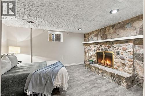Floor-to-ceiling stone fireplace with an integrated hearth, textured ceiling finish, recessed lighting, and wood-finish flooring - 81 East 23Rd Street, Hamilton, ON 