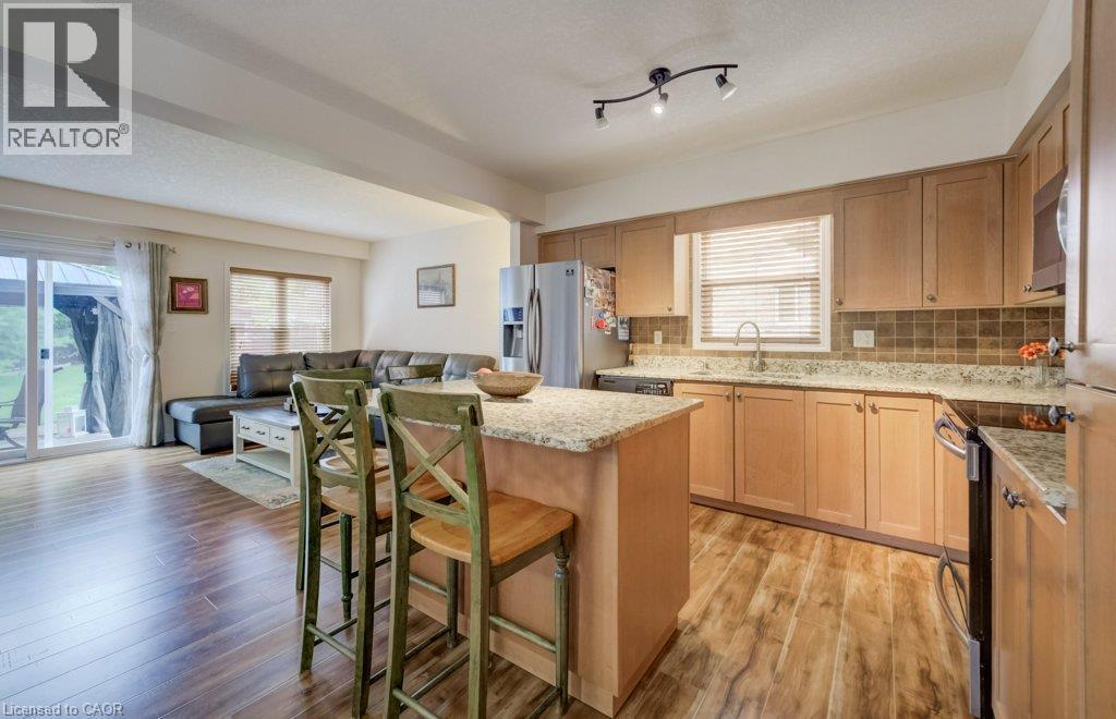 Kitchen featuring light-finish cabinetry, stone-patterned countertops, wood-finish flooring, a central island, and stainless steel appliances - 521 Snowdrop Court, Kitchener, ON