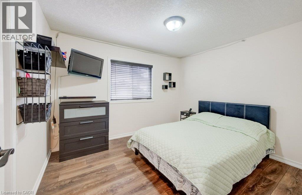 Bedroom featuring wood-finish flooring, a window with horizontal blinds, and a dome-style flush-mount ceiling light fixture - 521 Snowdrop Court, Kitchener, ON