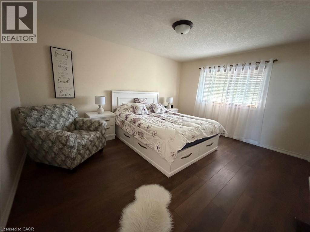 Room featuring wood-finish flooring, neutral wall tones, flush-mount ceiling lighting, and horizontal window blinds - 521 Snowdrop Court, Kitchener, ON